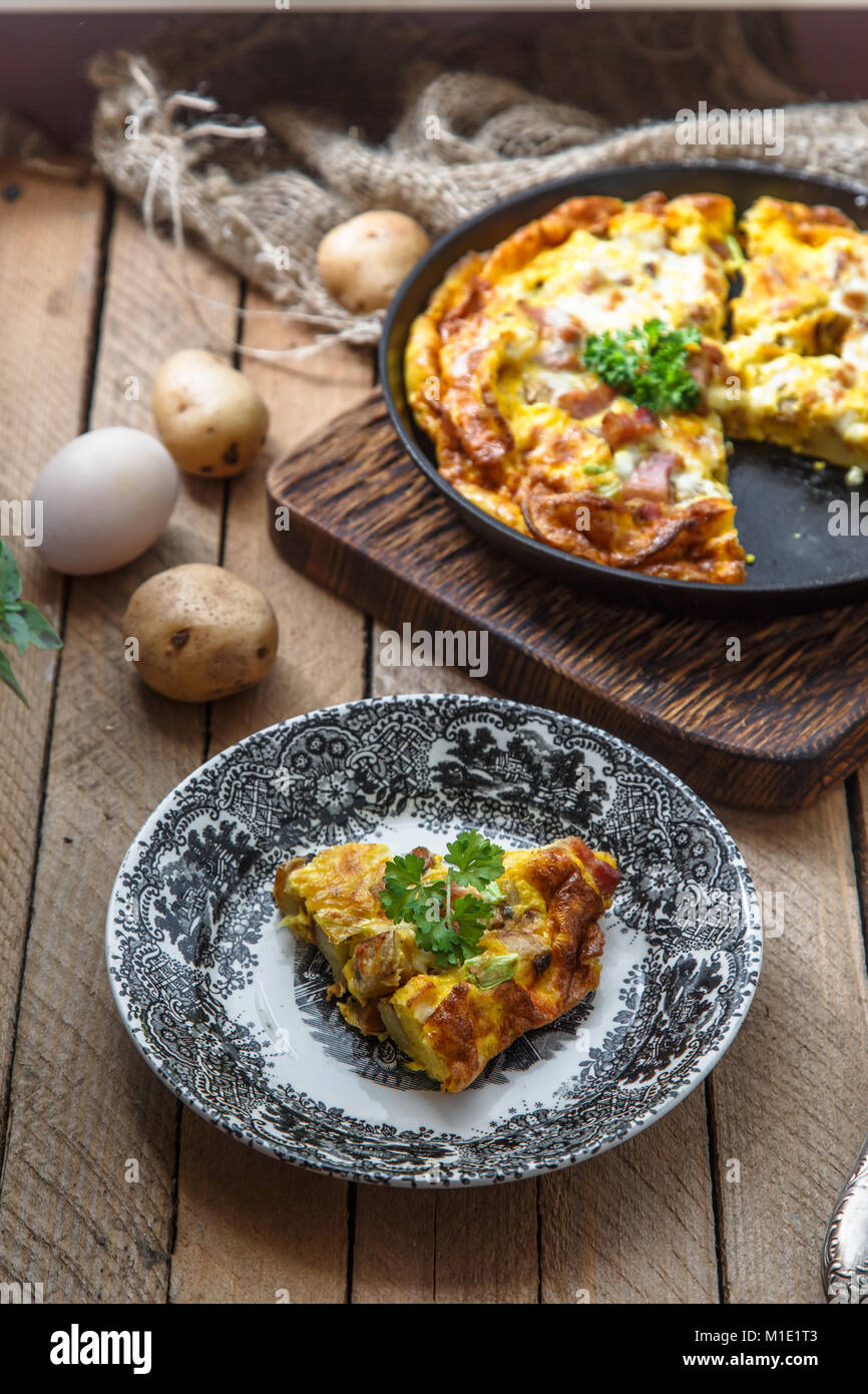 Un pezzo di francese omelette cotte Savoy con prosciutto e formaggio, patate e porri su una piastra, in stile rustico, vista dall'alto Foto Stock