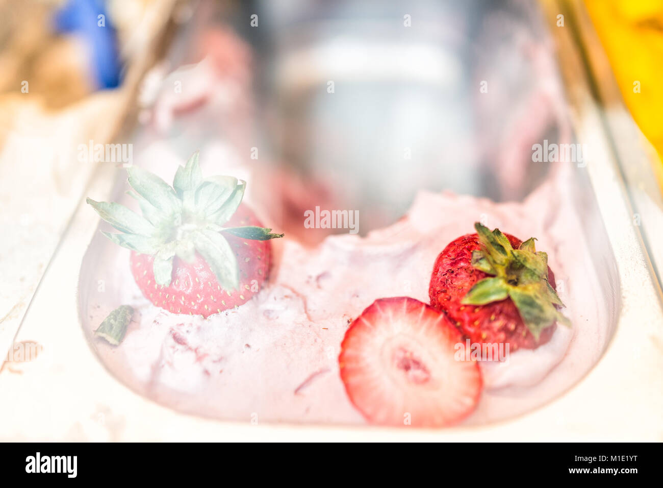 Macro closeup di rosa rosso sapore di fragola gelato Gelato con la frutta intera berry pezzi esposti nel negozio cafe shop con convogliatore in Italia, italiano Foto Stock