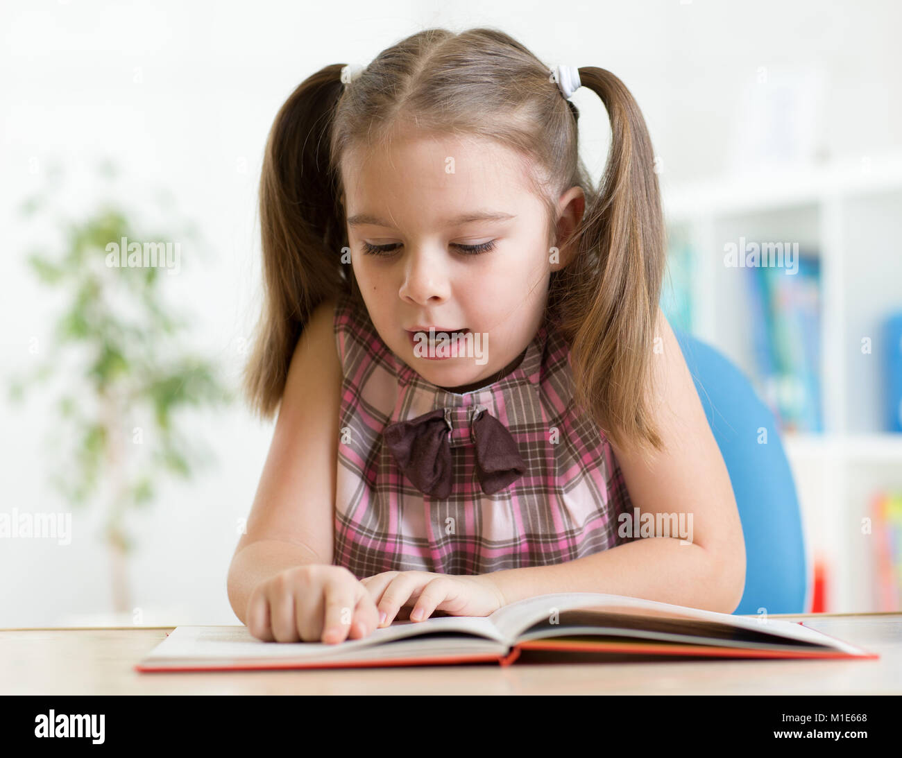 Kid ragazza la lettura di un libro a casa Foto Stock