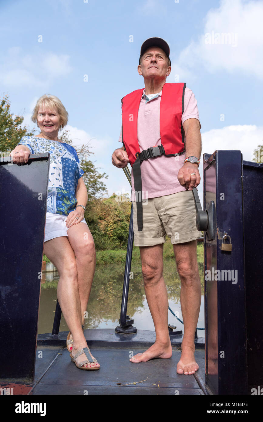 Coppia in una vacanza a galla la sterzatura di un narrowboat utilizzando il timone Foto Stock