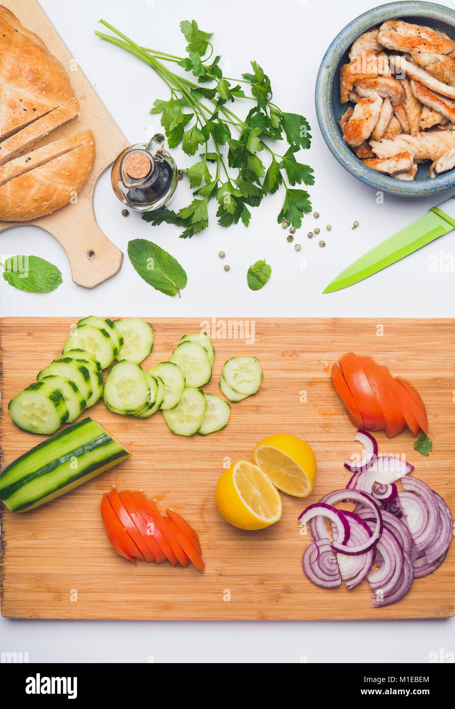 Pulire sano di mangiare o dieta alimenti concetto. Varie insalate ingredienti con bordo di taglio su sfondo bianco, vista dall'alto, laici piatta Foto Stock