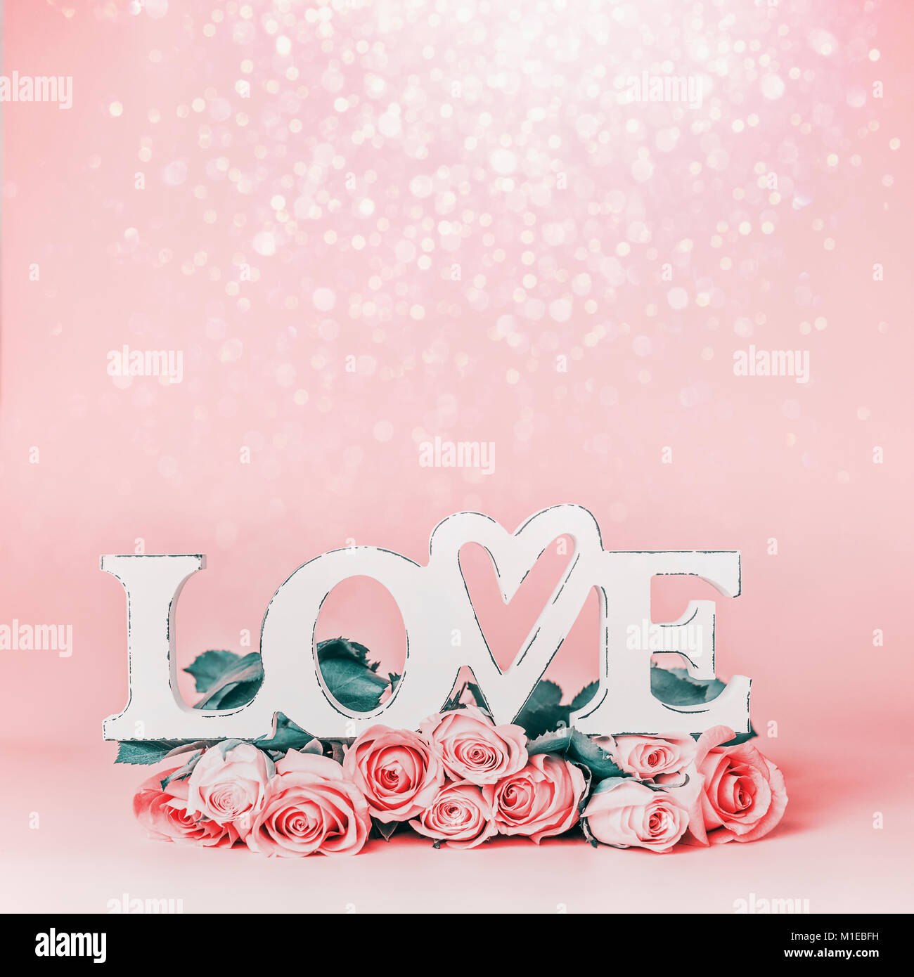 La parola amore pastello su sfondo rosa con un bellissimo mazzo di rose e bokeh , vista frontale. Creative vacanze femmina formato con spazio di copia per il messaggio di saluto Foto Stock