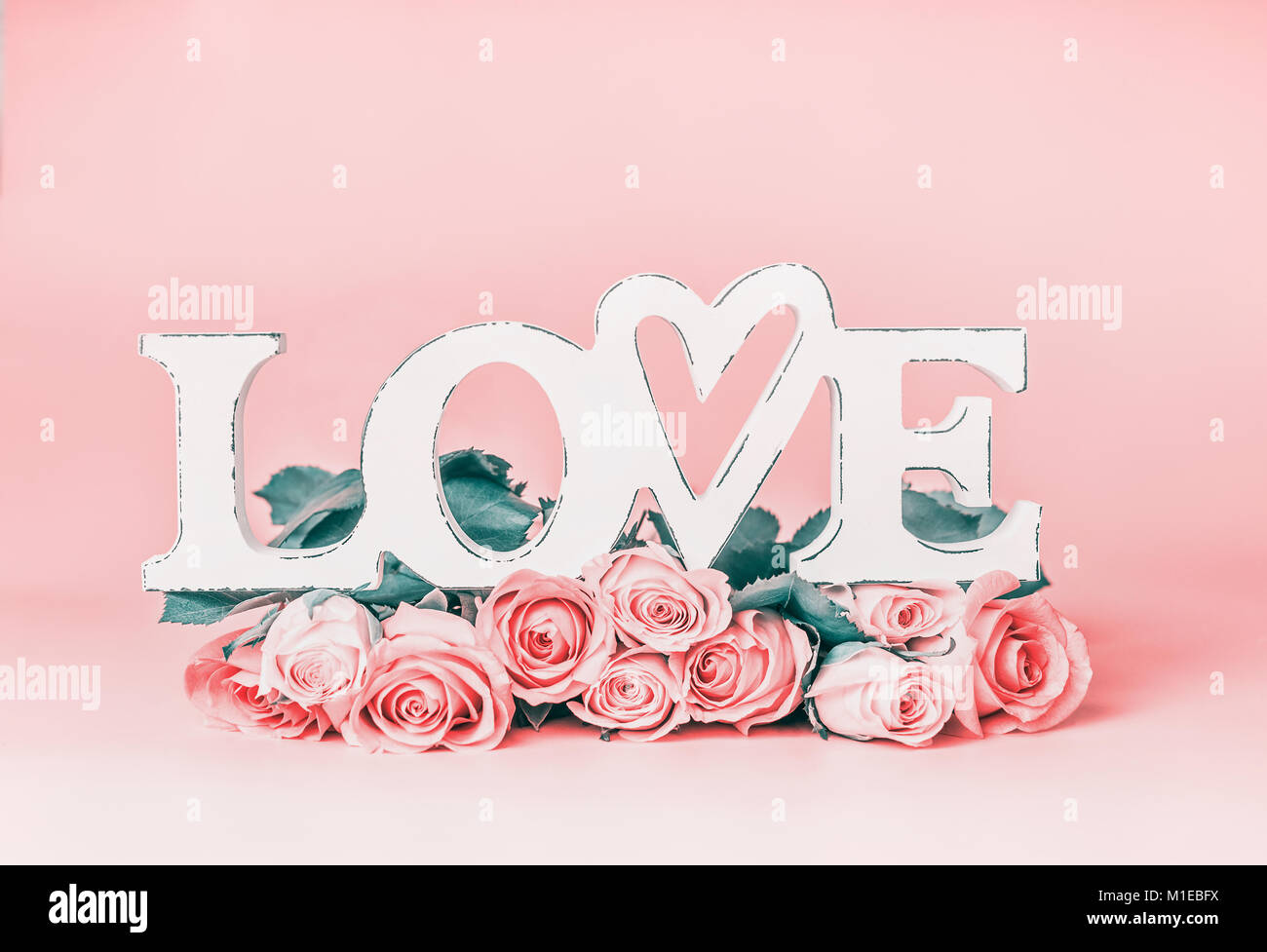 La parola amore pastello su sfondo rosa con rose mazzetto, vista frontale. Creative vacanze femmina formato con spazio di copia per il messaggio di saluto Foto Stock