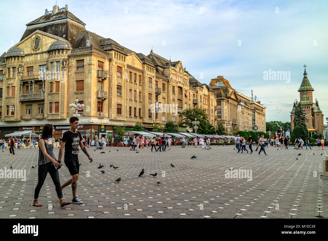 Coppia giovane attraversando a piedi Place Victory Square con la cattedrale ortodossa in background, Timisoara, Romania. Giugno2017. Foto Stock