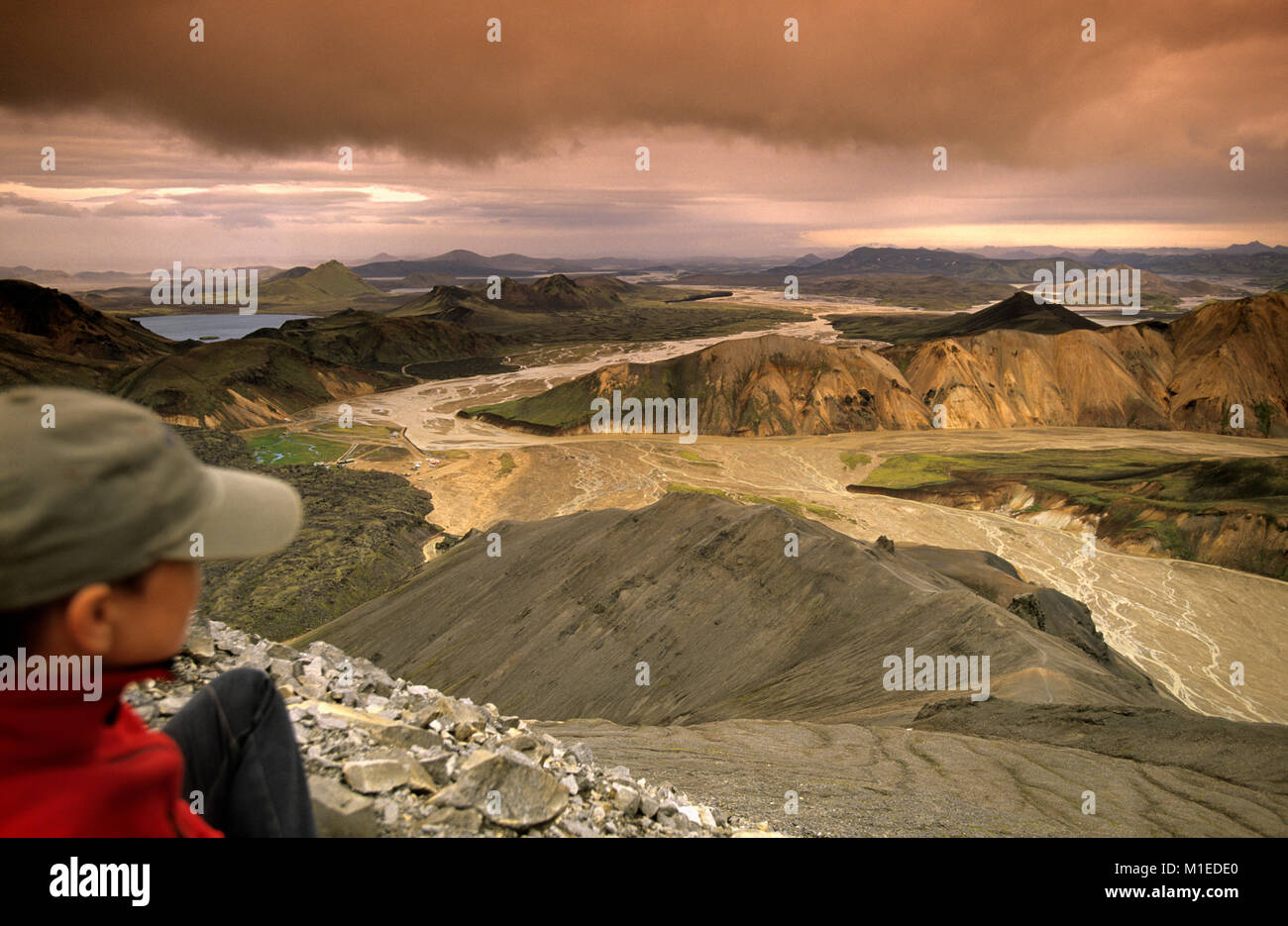 L'Islanda. Landmannalaugar Parco Nazionale. Tourist, escursionista donna guardando i campi di lava con il binocolo. Foto Stock