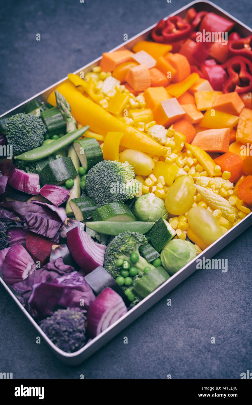 Tagliare le verdure colorate in una teglia da forno su un sfondo di ardesia Foto Stock