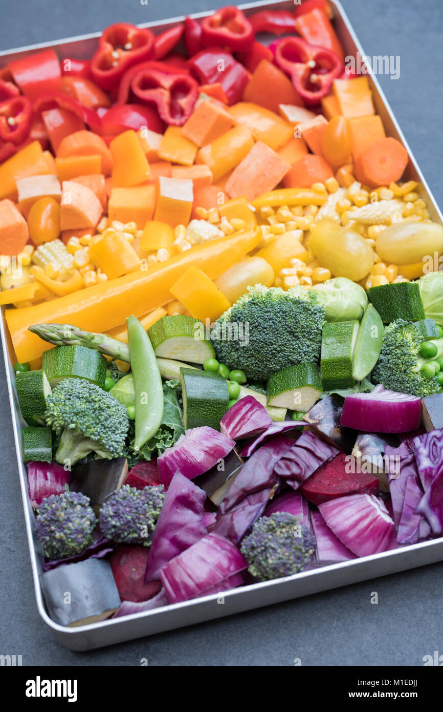 Tagliare le verdure colorate in una teglia da forno su un sfondo di ardesia Foto Stock