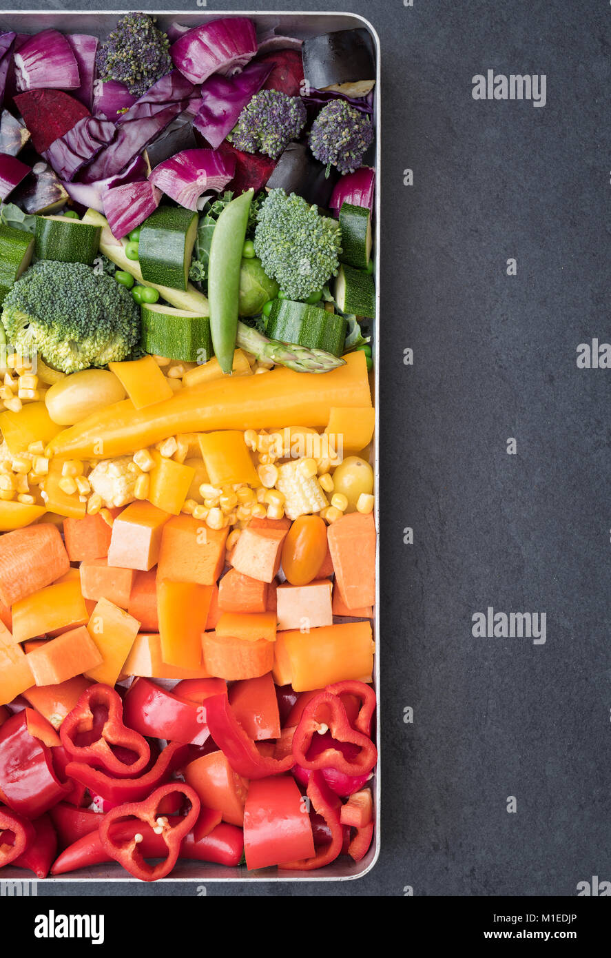 Tagliare le verdure colorate in una teglia da forno su un sfondo di ardesia Foto Stock