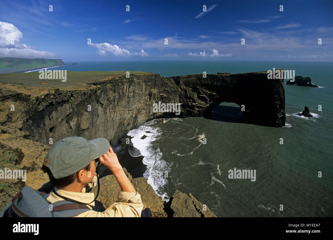 L'Islanda. Vik.L'altopiano roccioso Dyrholaey. Arch. Il turista. Donna con il binocolo sulla scogliera. Foto Stock