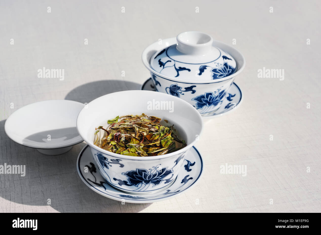 Due tazze di bianco tradizionale tè cinese con la peonia bianco sul tavolo bianco, lo spazio di testo Foto Stock
