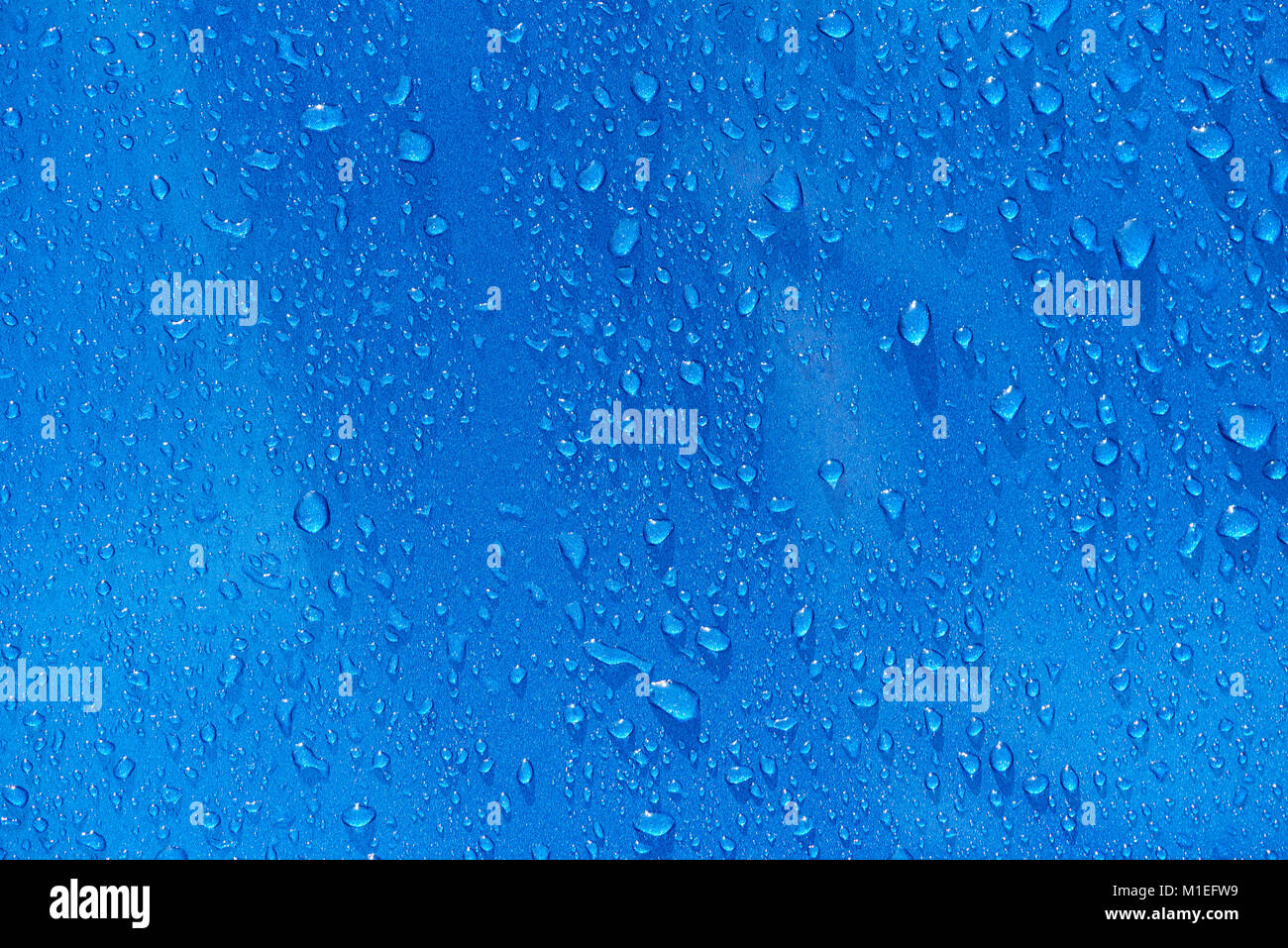 Gocce di pioggia sul metallo blu sullo sfondo di close-up. Gocce d'acqua texture blu Foto Stock