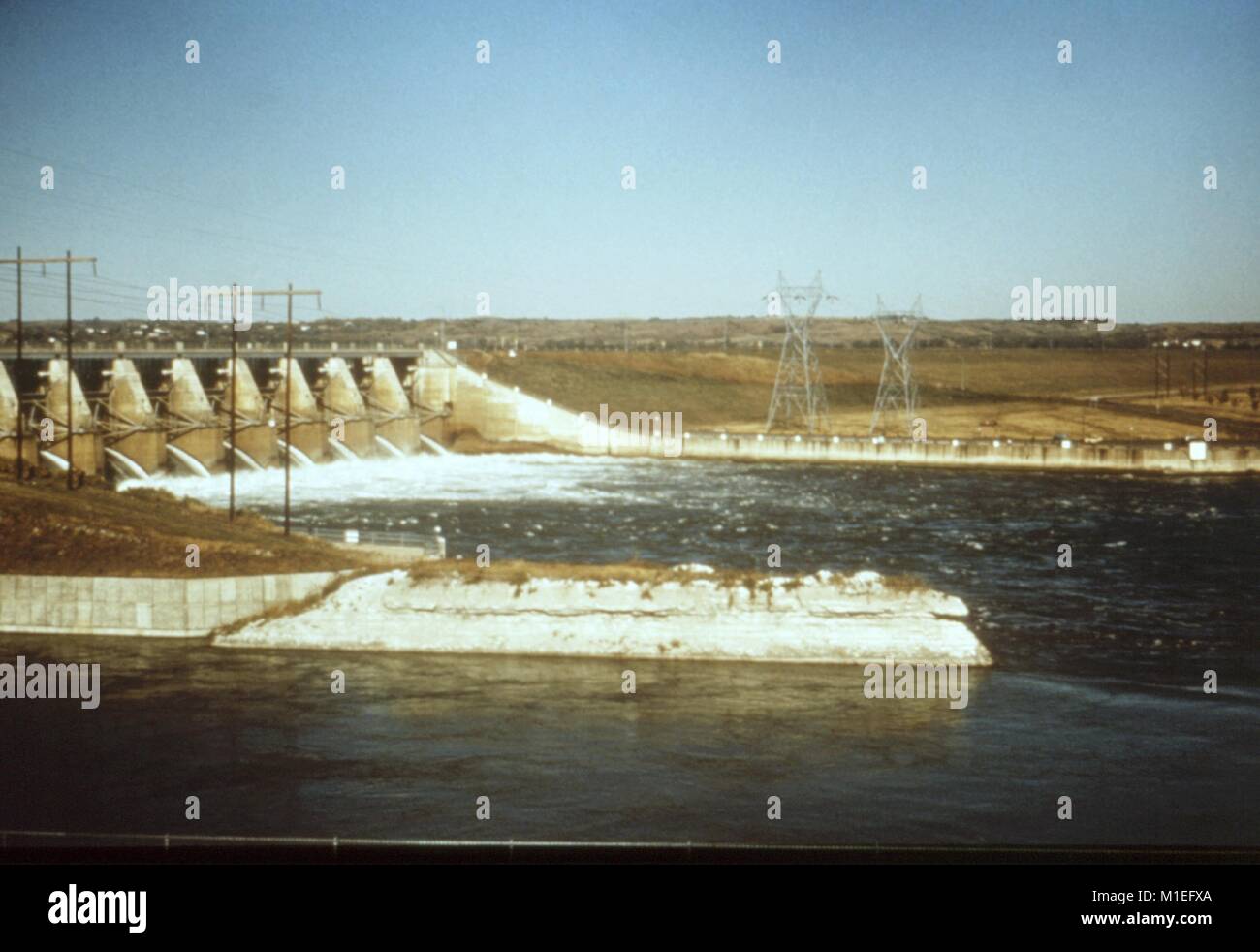 Fotografia paesaggio di sfioratori in corrispondenza di una diga idroelettrica, con linee di alimentazione aeree e tralicci anche visibile, preso come parte di un procedimento di indagine nel vettore di malattie, punto Gavins Dam, Lewis e Clark Lake, Nebraska, 1976, 1976. Immagine cortesia CDC. () Foto Stock