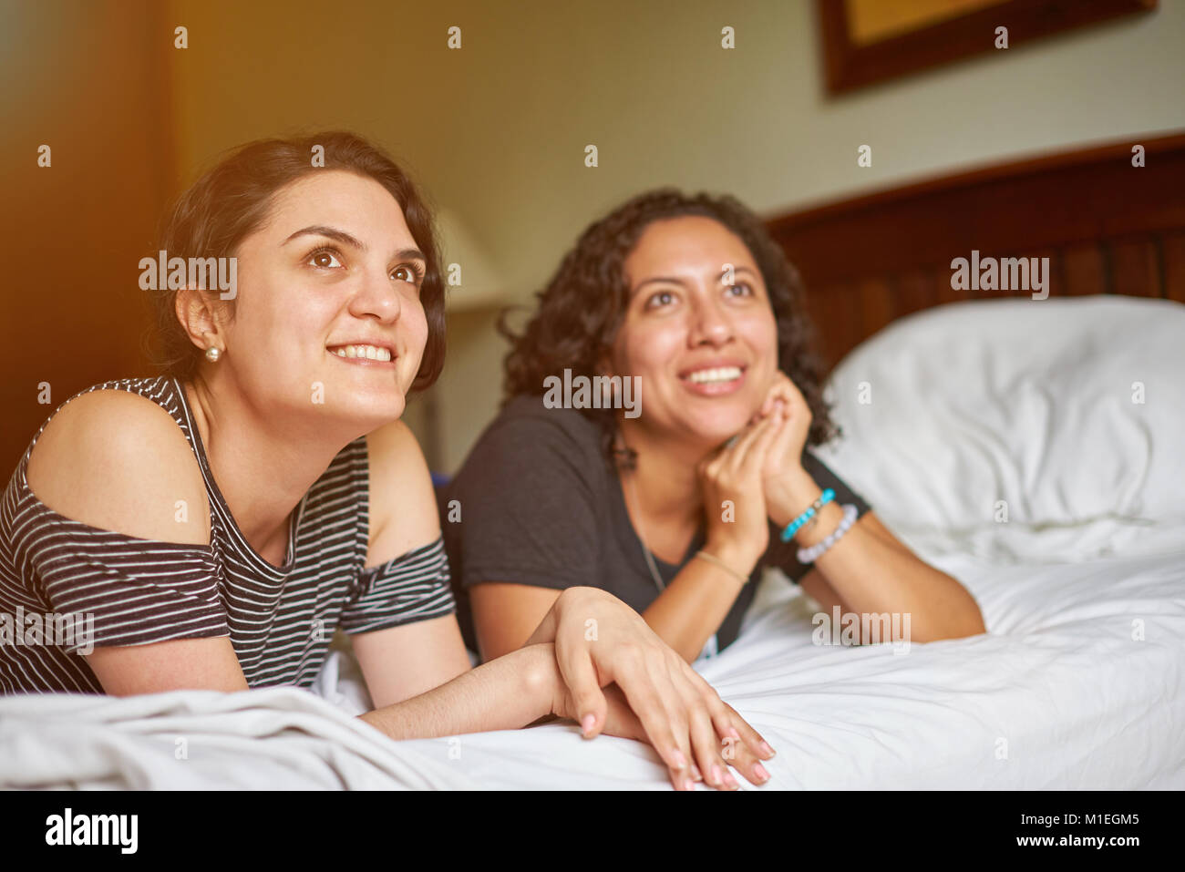 Due amiche giaceva sul letto e guarda nella parte anteriore Foto Stock