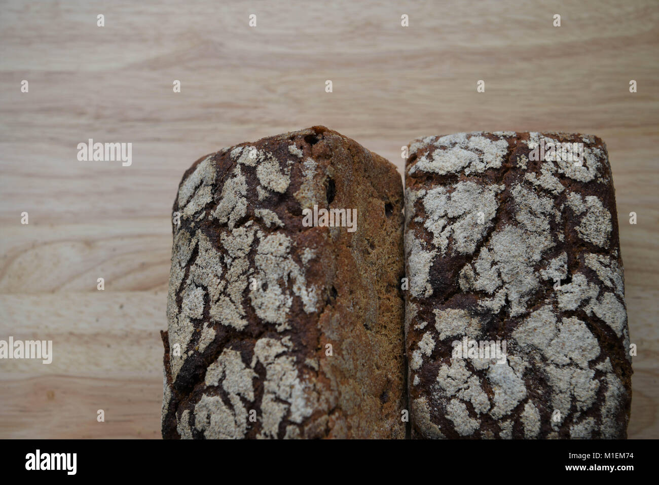 Cibo fatto in casa pane artigianale aromatizzata con uva passa e segale per il colore scuro e con pattern di farina alto su un rustico di legno naturale scheda di taglio Foto Stock