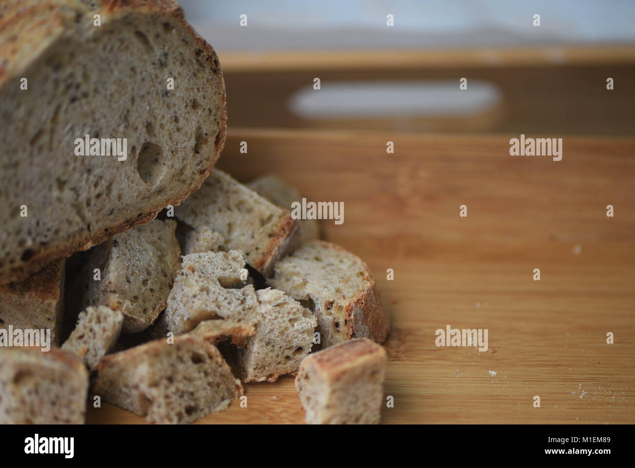 Cibo fatto in casa pane artigianale pane appena sfornato e alcuni pezzi tagliati a cubetti su un vassoio in legno pronto a mangiare Foto Stock