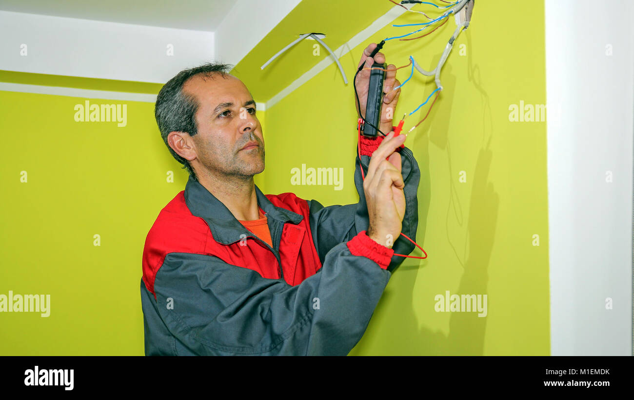 Elettricista installa il cablaggio nel nuovo appartamento. Cablaggio di una bocca di uscita di una scatola elettrica. Foto Stock
