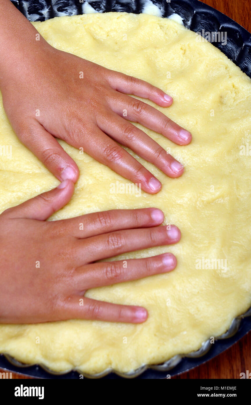 Bambino con le mani in mano la stesura di un grafico a torta la torta in una teglia Foto Stock