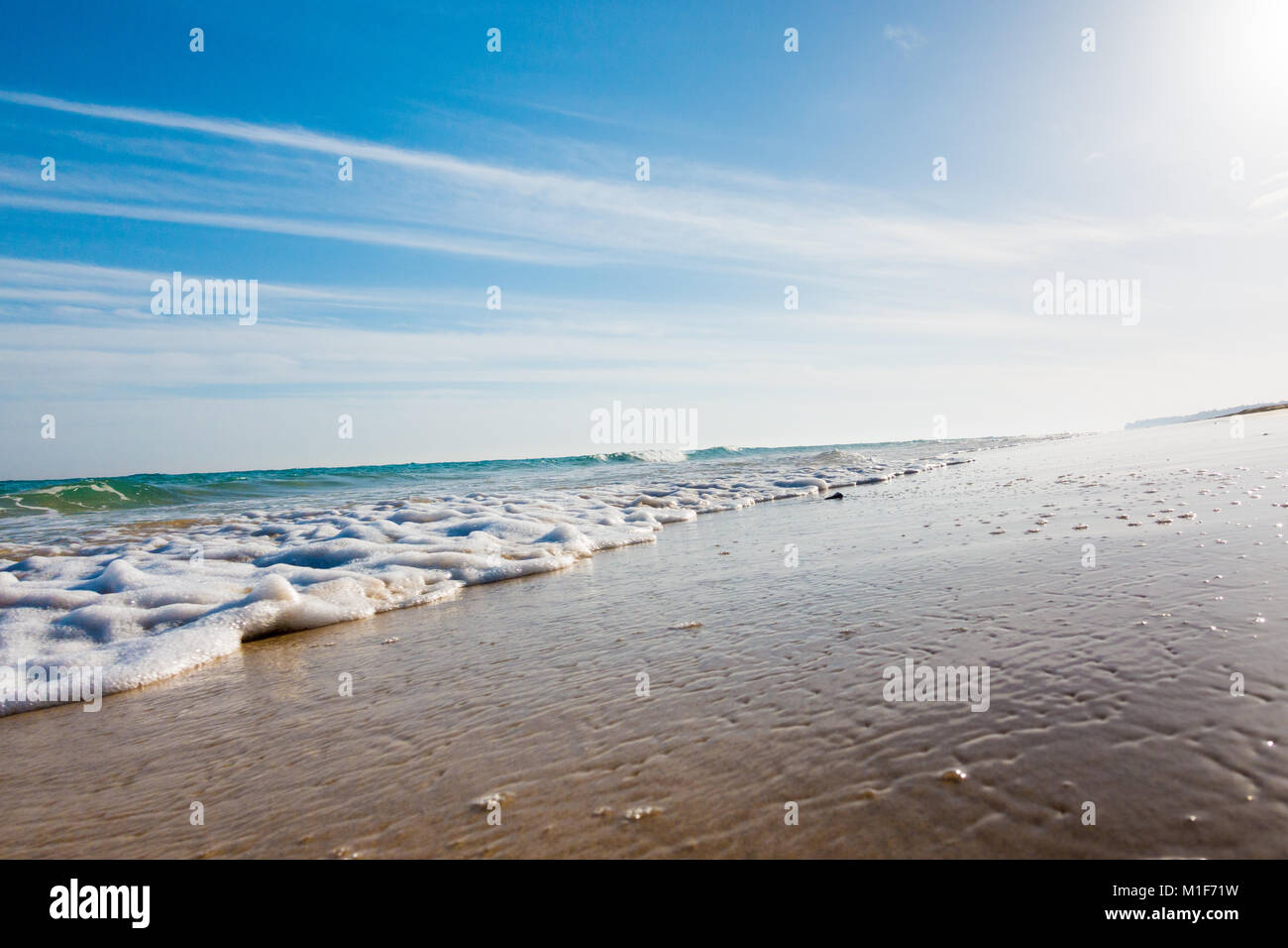 Mare calmo e navigare su di una spiaggia di sabbia. estate mare nel tempo molto soleggiato con cielo blu. Una bellissima spiaggia di sabbia e le onde trasparenti Foto Stock