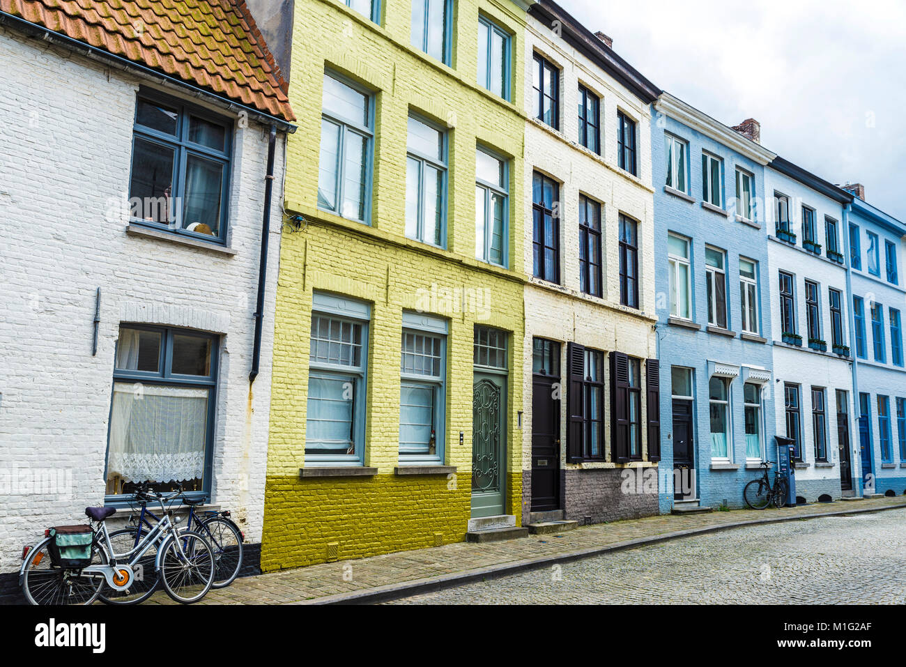 Le biciclette parcheggiate nella parte anteriore del vecchio colorate case tradizionali su una strada del centro storico della città medievale di Bruges, Belgio Foto Stock