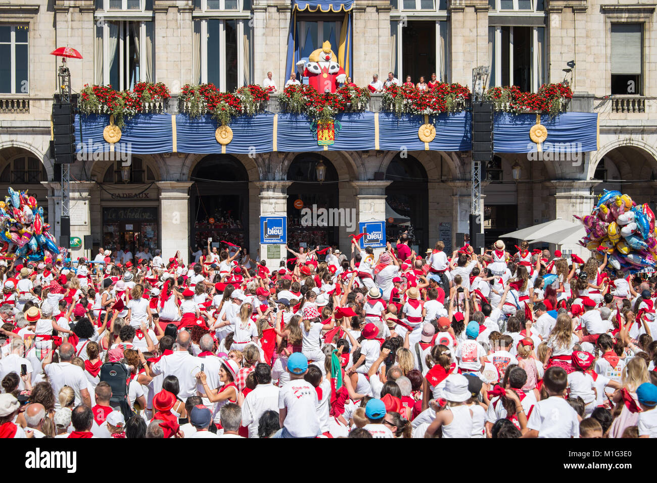 La folla di persone vestite di bianco e rosso il tifo Re Leon sul balcone al festival estivo di Bayonne (Fetes de Bayonne), Francia Foto Stock