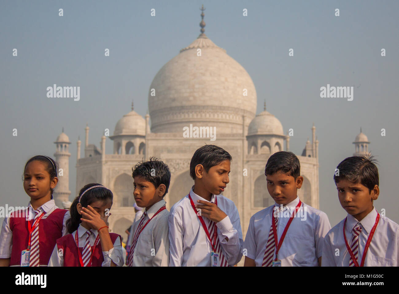 Indian School bambini cercando di noia e alimentato fino a un viaggio al Taj Mahal di Agra, pronunciare Pradesh, India, in bianco e rosso uniformi scolastiche Foto Stock