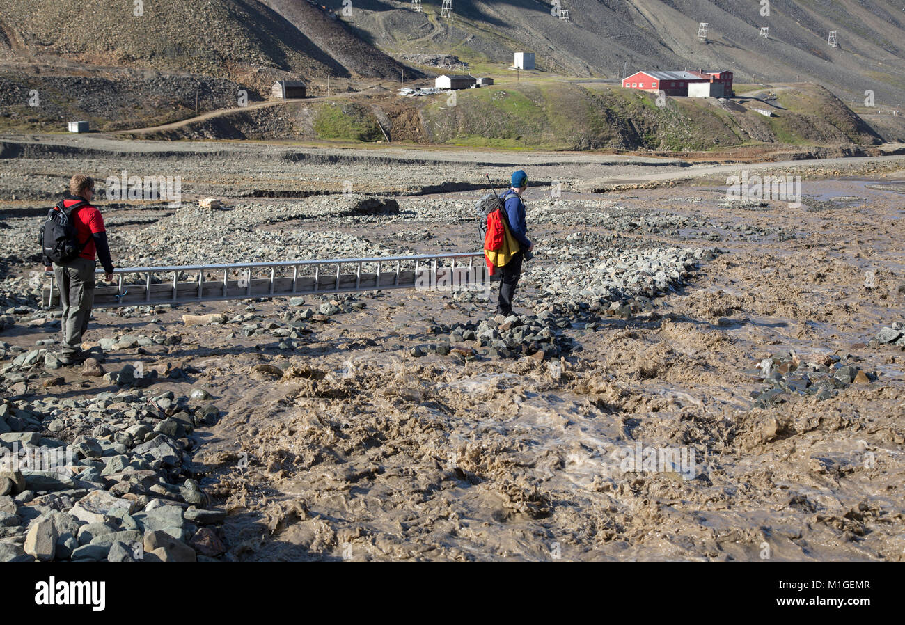 Longyearbean, Svalbard, Norvegia, Luglio 18th, 2013: escursionisti stanno cercando di trovare un modo per attraversare in rapido movimento di fiume glaciale Foto Stock