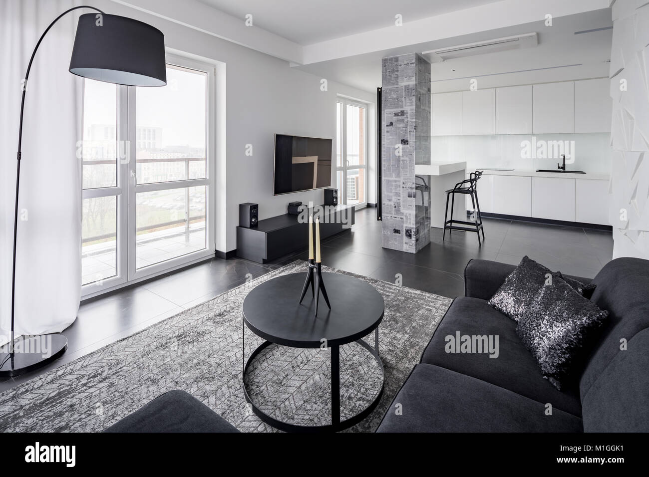 Home interno con divano nero, tavola rotonda e lampada Foto Stock