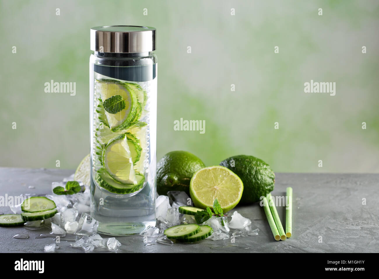 Infuso con acqua di calce e il cetriolo in una bottiglia di vetro Foto Stock
