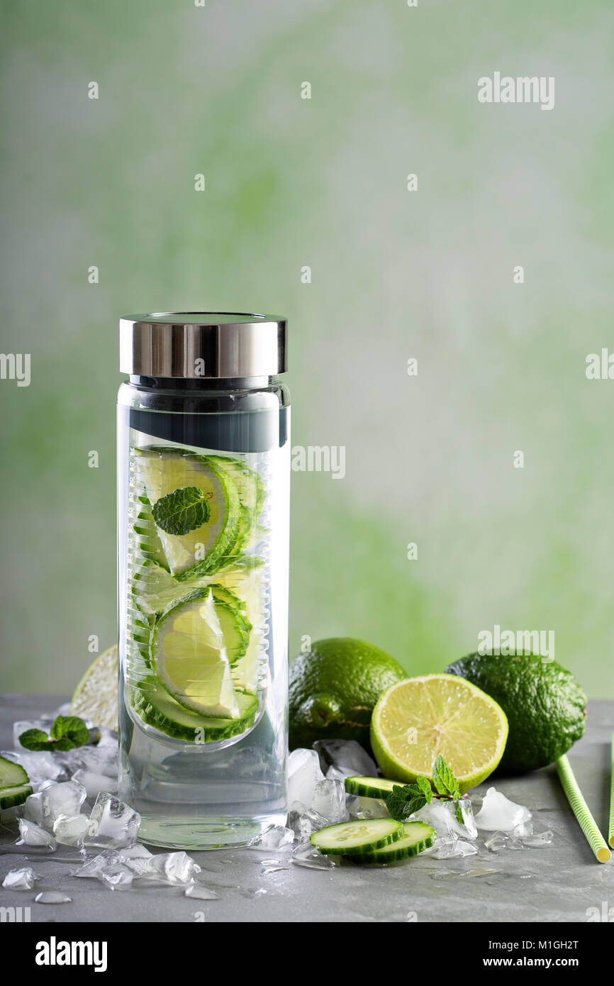 Infuso con acqua di calce e il cetriolo in una bottiglia di vetro Foto Stock