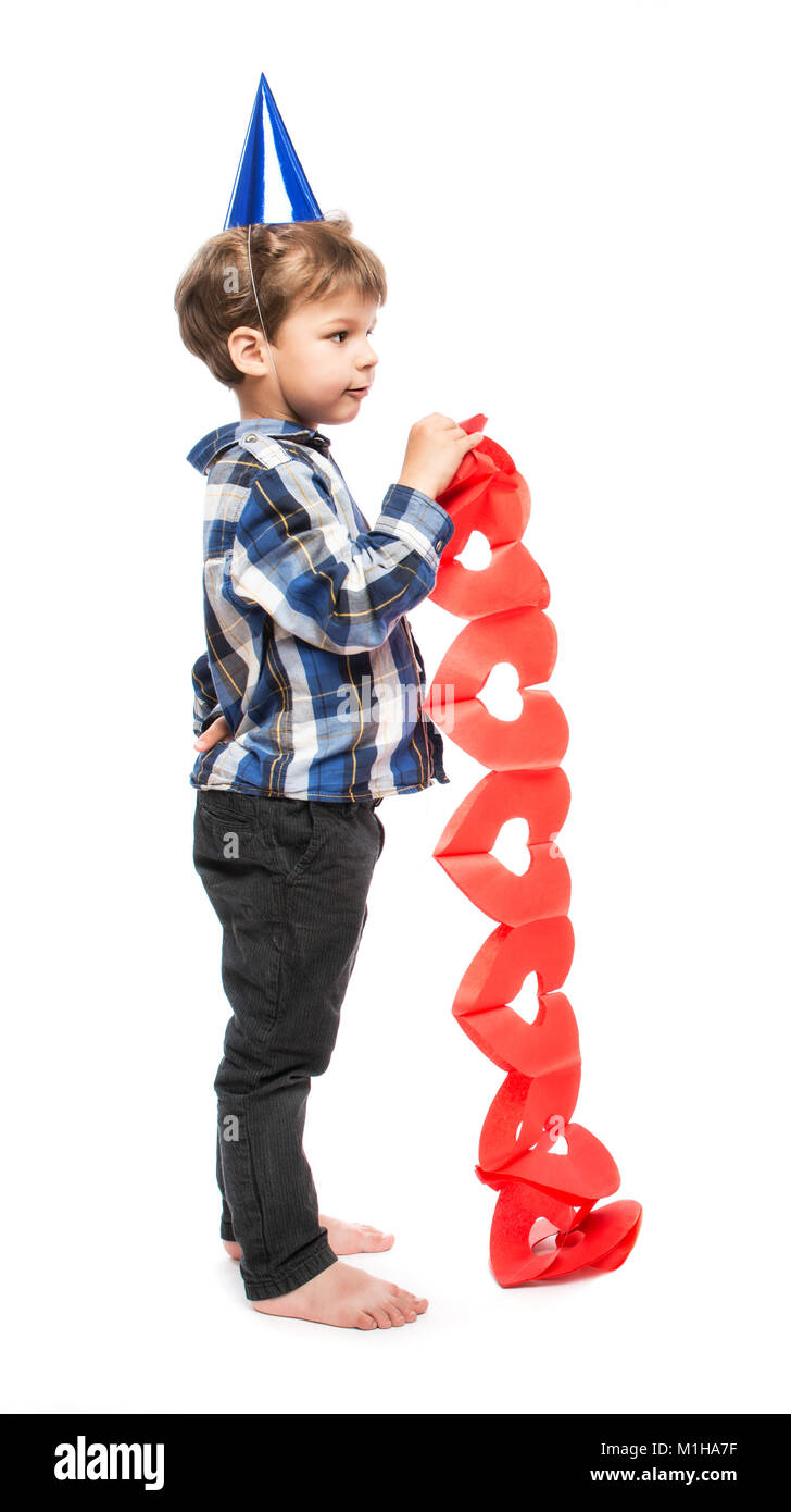 Carino piccolo ragazzo in compleanno hat tenendo la carta ghirlanda di cuori rossi su sfondo bianco Foto Stock