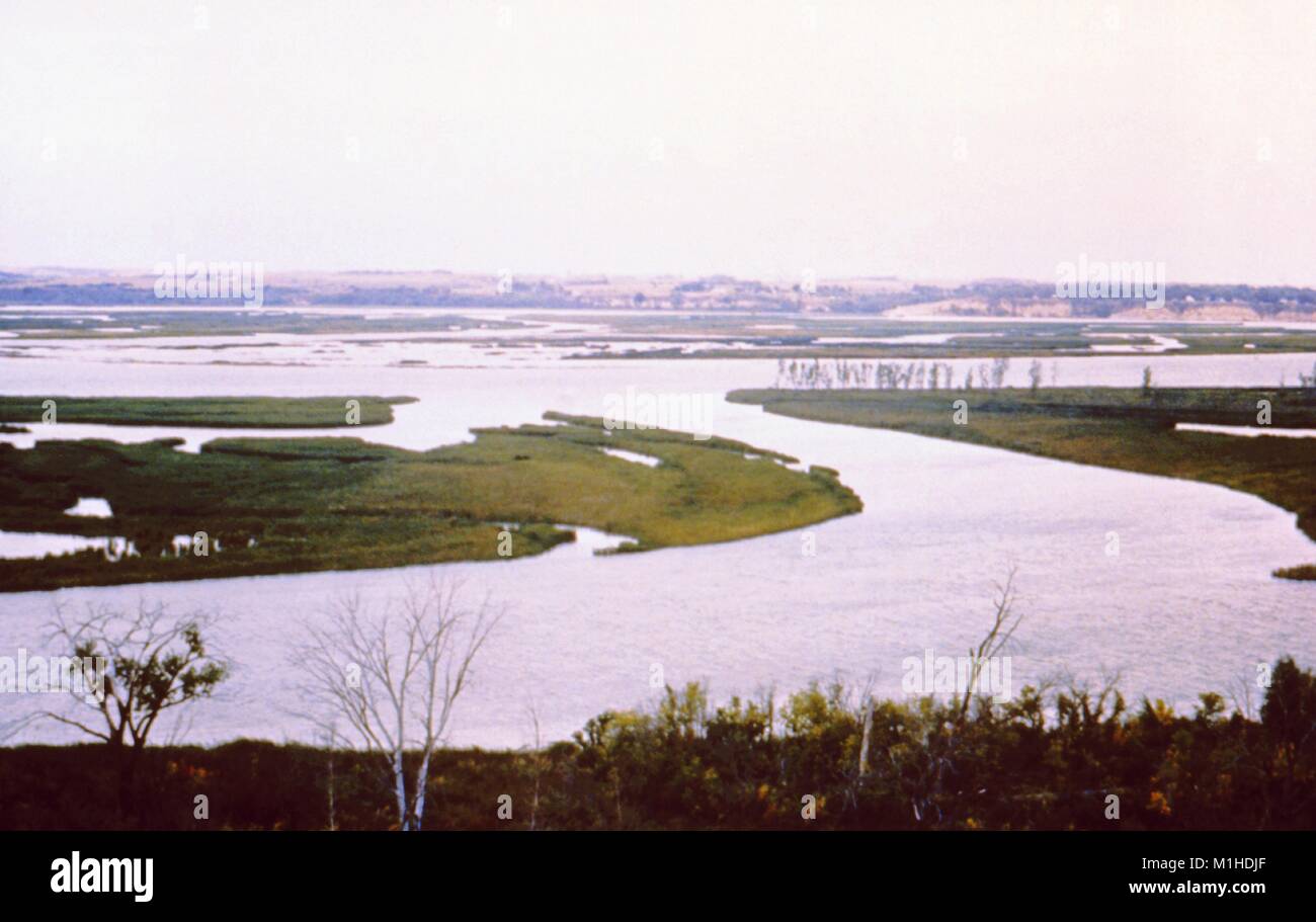 Fotografia paesaggio delle isole erbose formata entro un lago serbatoio impostato nel piatto, terreni erbosi, con scogliere visibile in background, preso come parte di un procedimento di indagine nel vettore di malattie, Lewis e Clark Lago, Santee, Nebraska, 1976. Immagine cortesia CDC. () Foto Stock