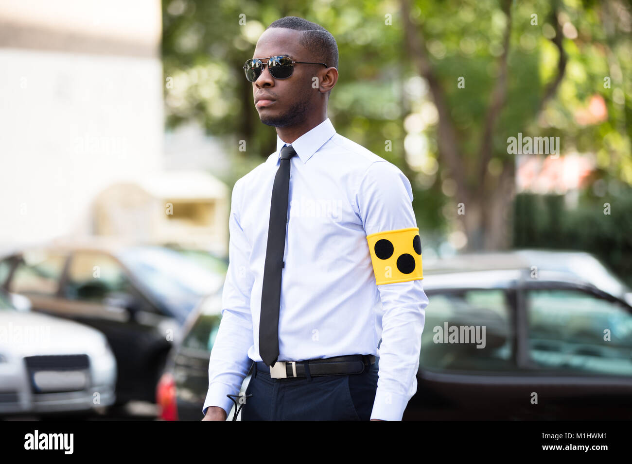 Ritratto di cieco indossando giallo fascia per il braccio e gli occhiali da sole in piedi all'aperto Foto Stock