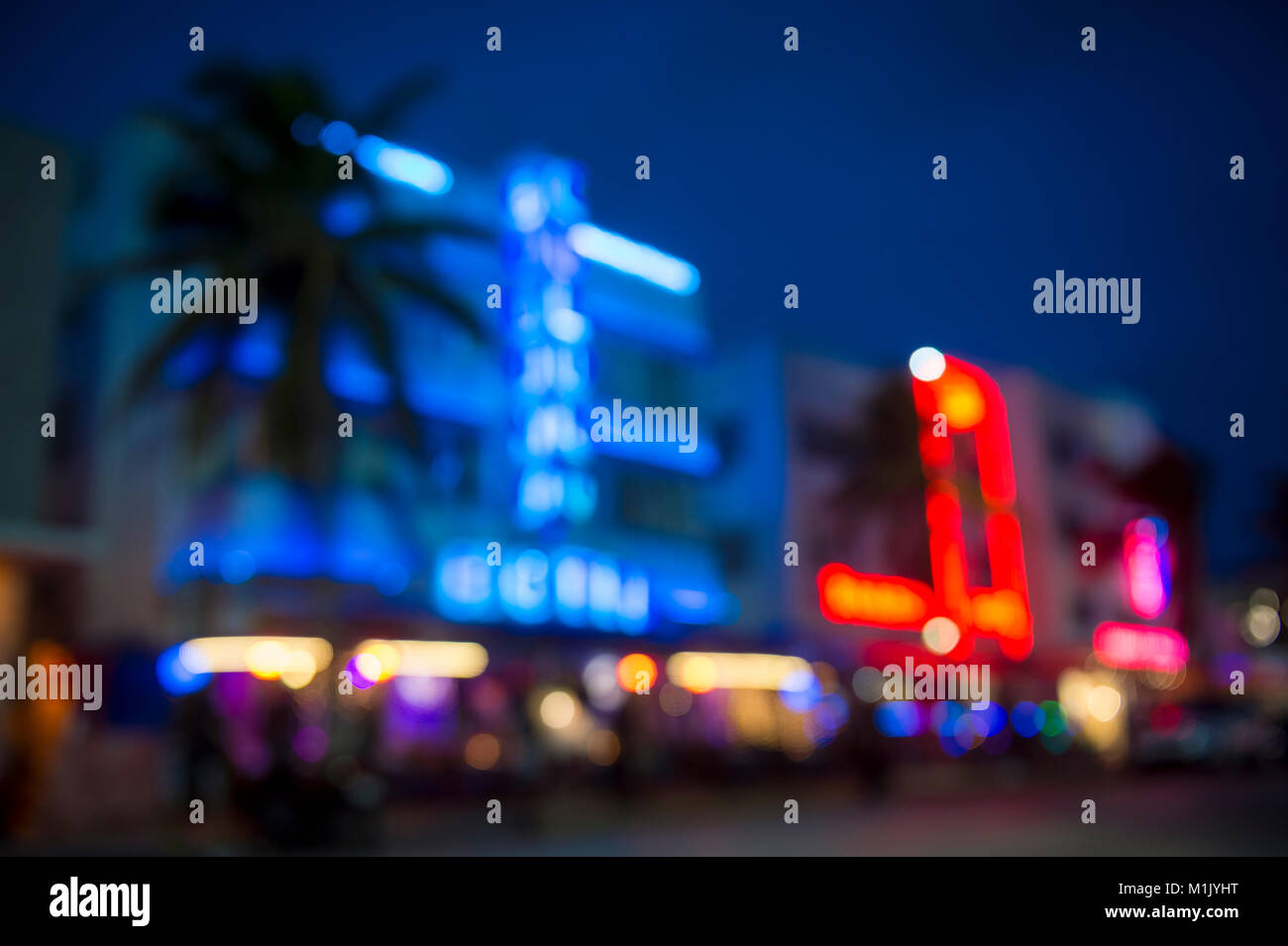 Sfocati vista del tramonto di palme e luci al neon della mitica Ocean Drive Art Deco storico quartiere della vita notturna di South Beach, Miami, Florida Foto Stock