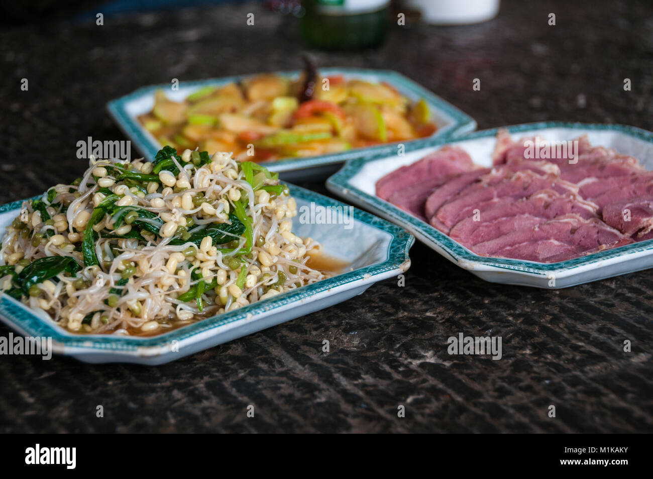 Home cucinato cibo cinese nella zona rurale di Xi'an, Shaanxi Province, Cina. Un piatto di germogli di soia, un bollito di manzo fette e dietro un piatto o Foto Stock