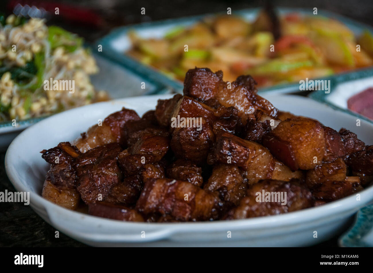 Home cucinato cibo cinese nella zona rurale di Xi'an, Shaanxi Province, Cina. Piatto principale hongshaorou (brasati di carne di maiale) con un piatto di germogli di soia, un piatto Foto Stock