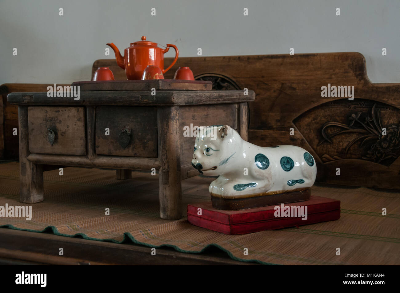 Un porcellanato set per il tè e il gatto su un tradizionale in legno intagliato letto. Parte della collezione privata di Wu Jianguo un ex Guardie rosse. La zona rurale di Xi' Foto Stock