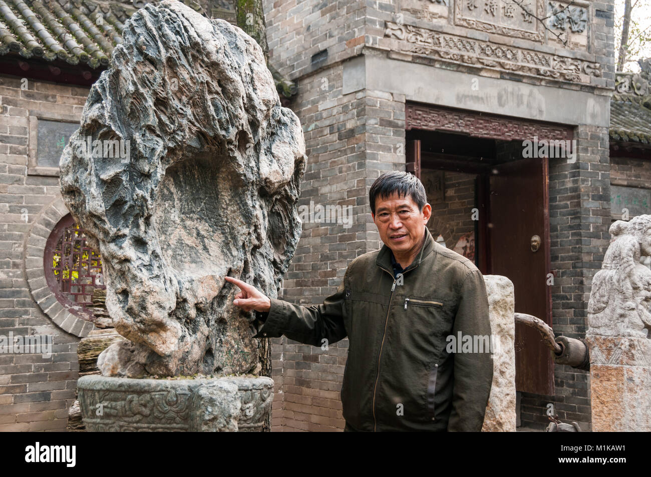 Wu Jianguo con un vecchio decorativi in pietra parte della sua collezione in parte rurale di Xi'an. Foto Stock