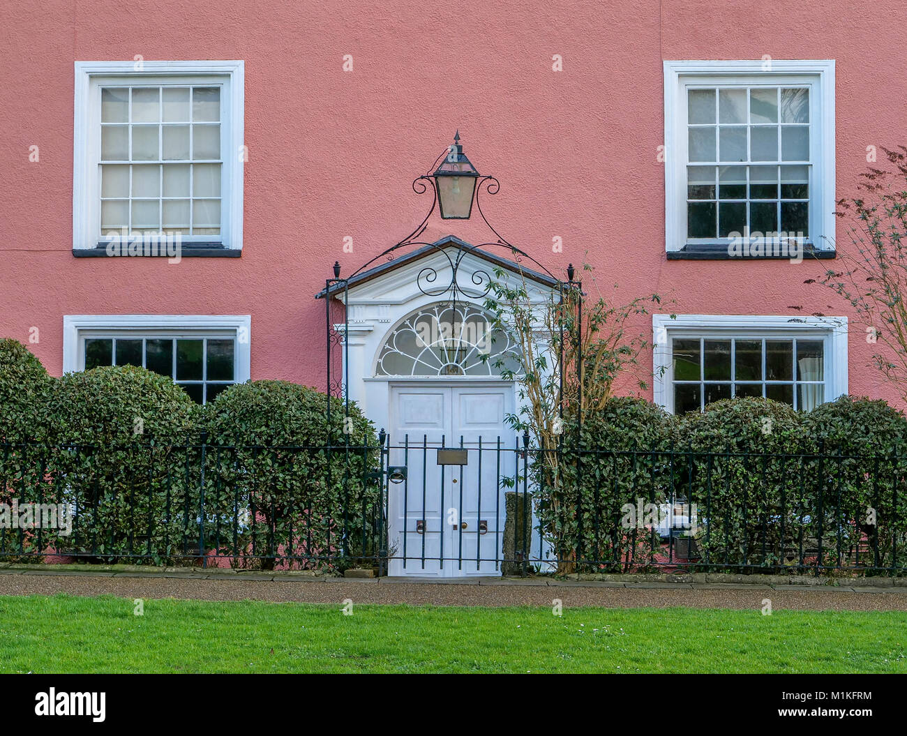 Dipinto di rosa Georgian House con letti in ferro battuto con porta arcuata con lampada sul verde della Cattedrale di Wells Somerset REGNO UNITO Foto Stock