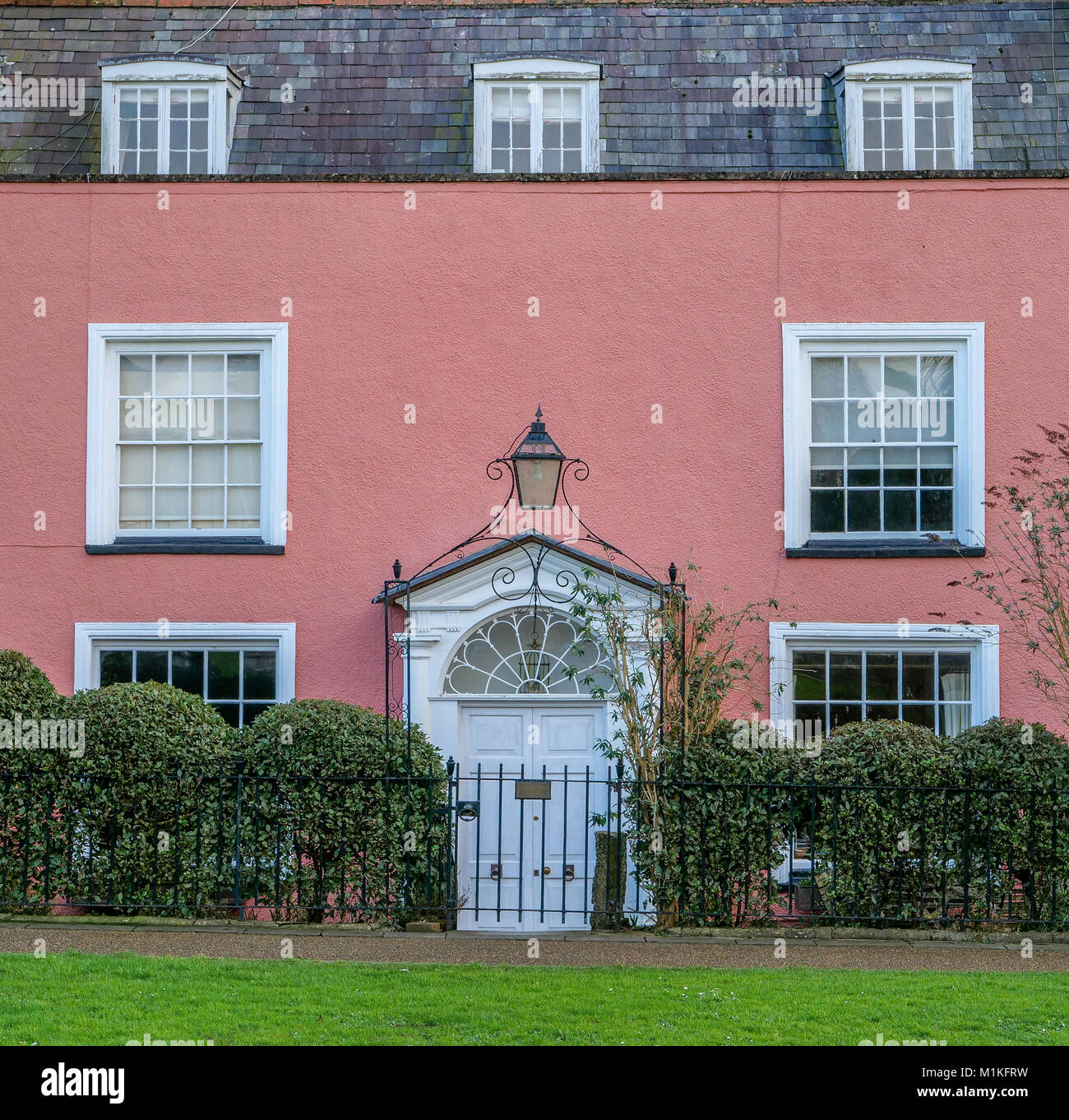Dipinto di rosa Georgian House con letti in ferro battuto con porta arcuata con lampada sul verde della Cattedrale di Wells Somerset REGNO UNITO Foto Stock
