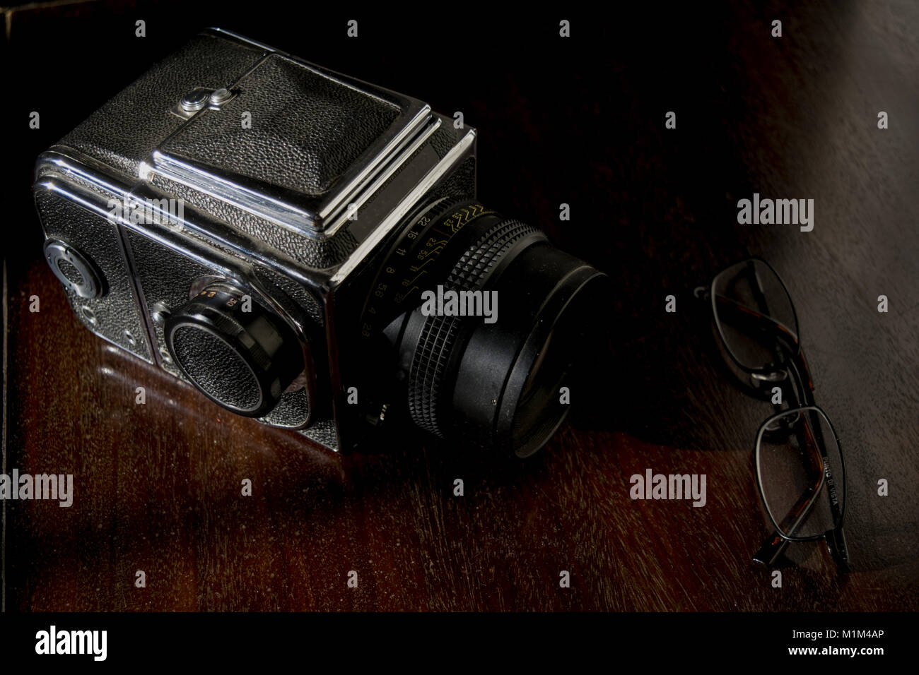 Vecchia macchina fotografica e una coppia di specifiche sulla credenza in legno Foto Stock