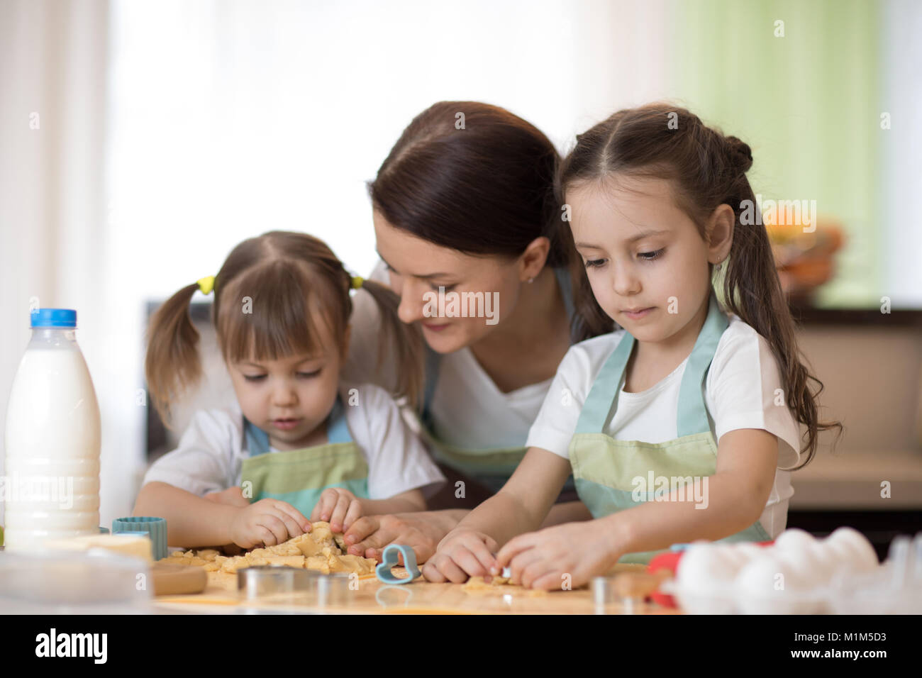 Felice famiglia amorevole madre e le sue figlie sono la preparazione di prodotti da forno insieme. La mamma e i bambini sono i biscotti di cottura e divertirsi in cucina. Homema Foto Stock