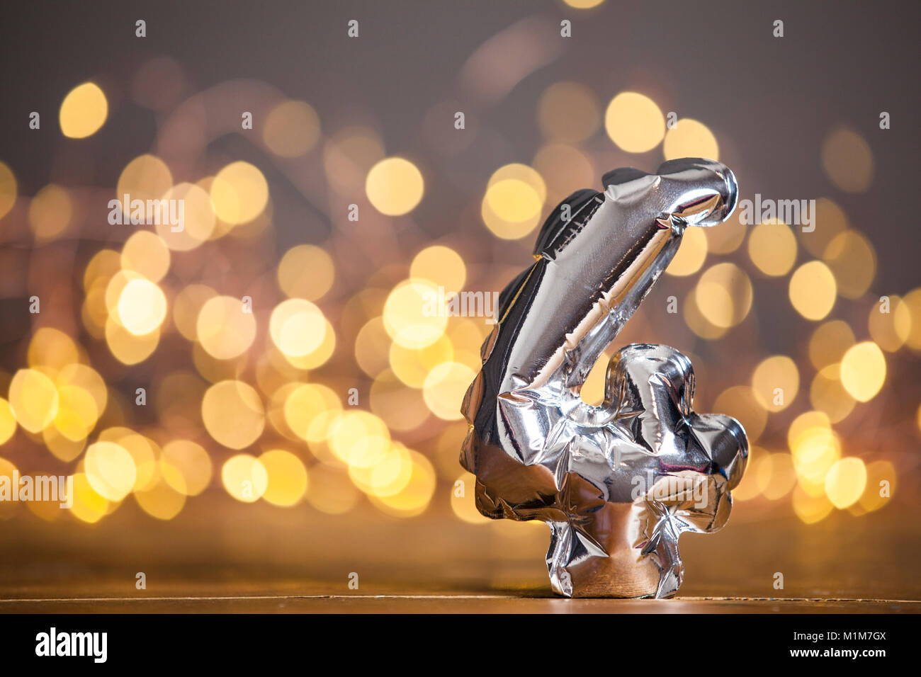 Numero d'argento 4 celebrazione palloncino lamina contro sfocato sfondo luminoso Foto Stock