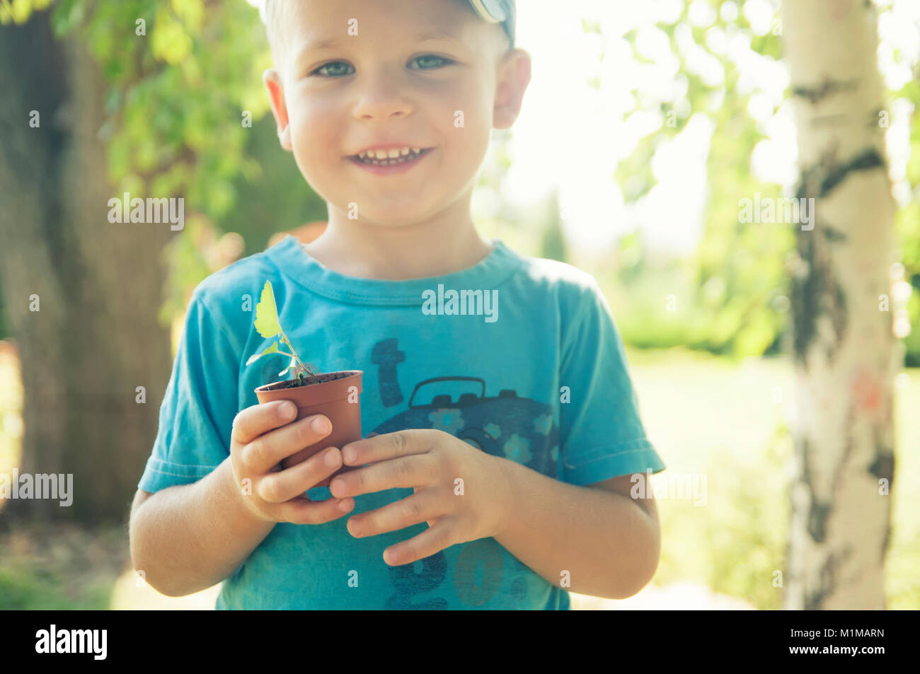 Il bambino è in possesso di un vaso di fiori con una pianta piccola Foto Stock
