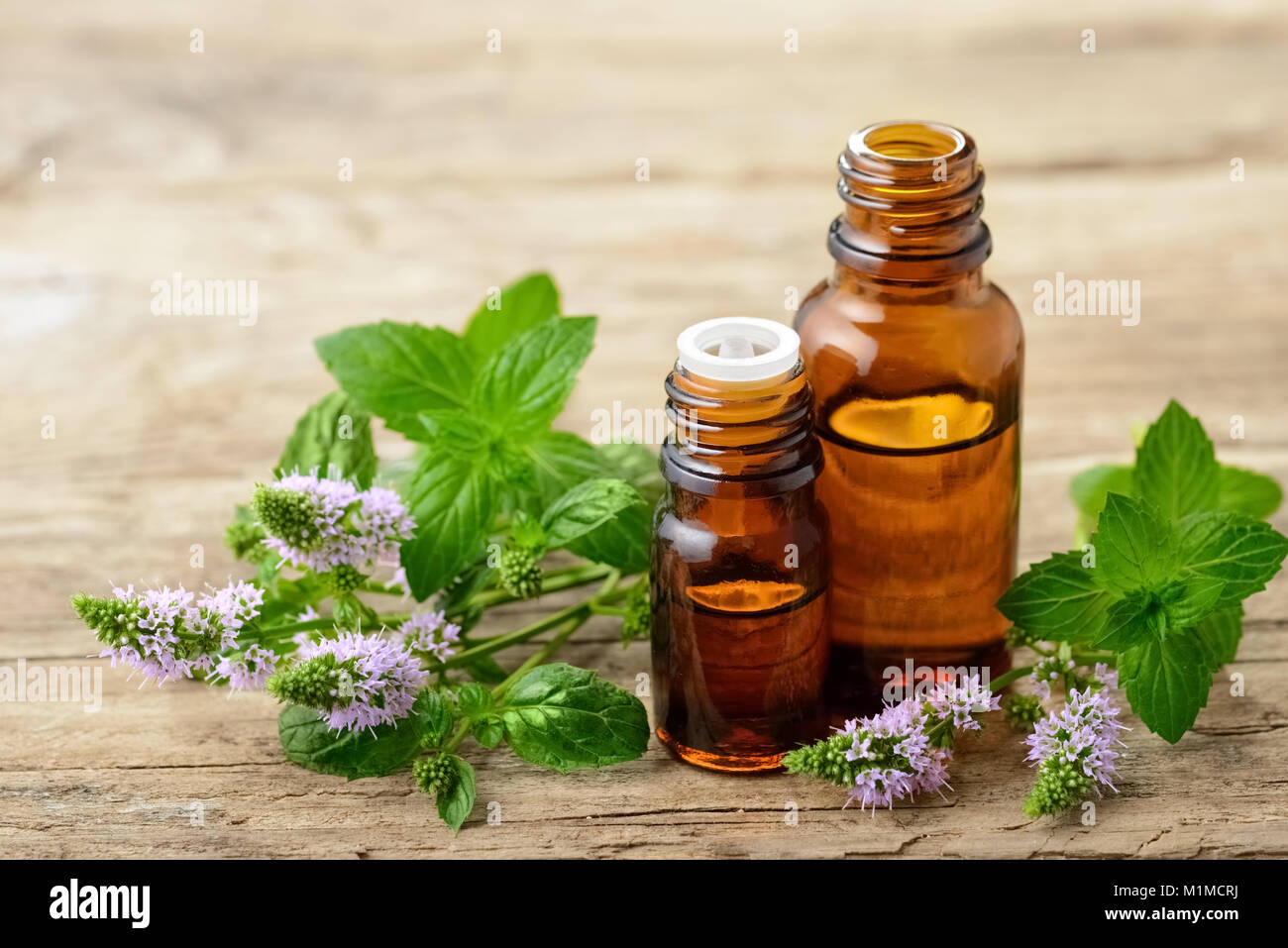 La menta piperita olio essenziale e menta piperita fresca fiori sul tavolo di legno Foto Stock