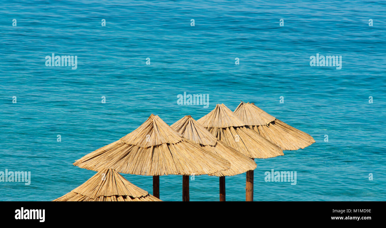 Una perfetta vacanza estiva destinazione : spiaggia ombrelloni di paglia con il mare sullo sfondo , alto angolo di visione Foto Stock