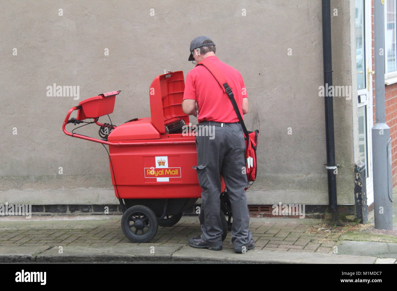 Un rosso ROYAL MAIL DELIVERY carrello carrello con il postino lo smistamento IN UNA STRADA DI FLEETWOOD Town Center Foto Stock