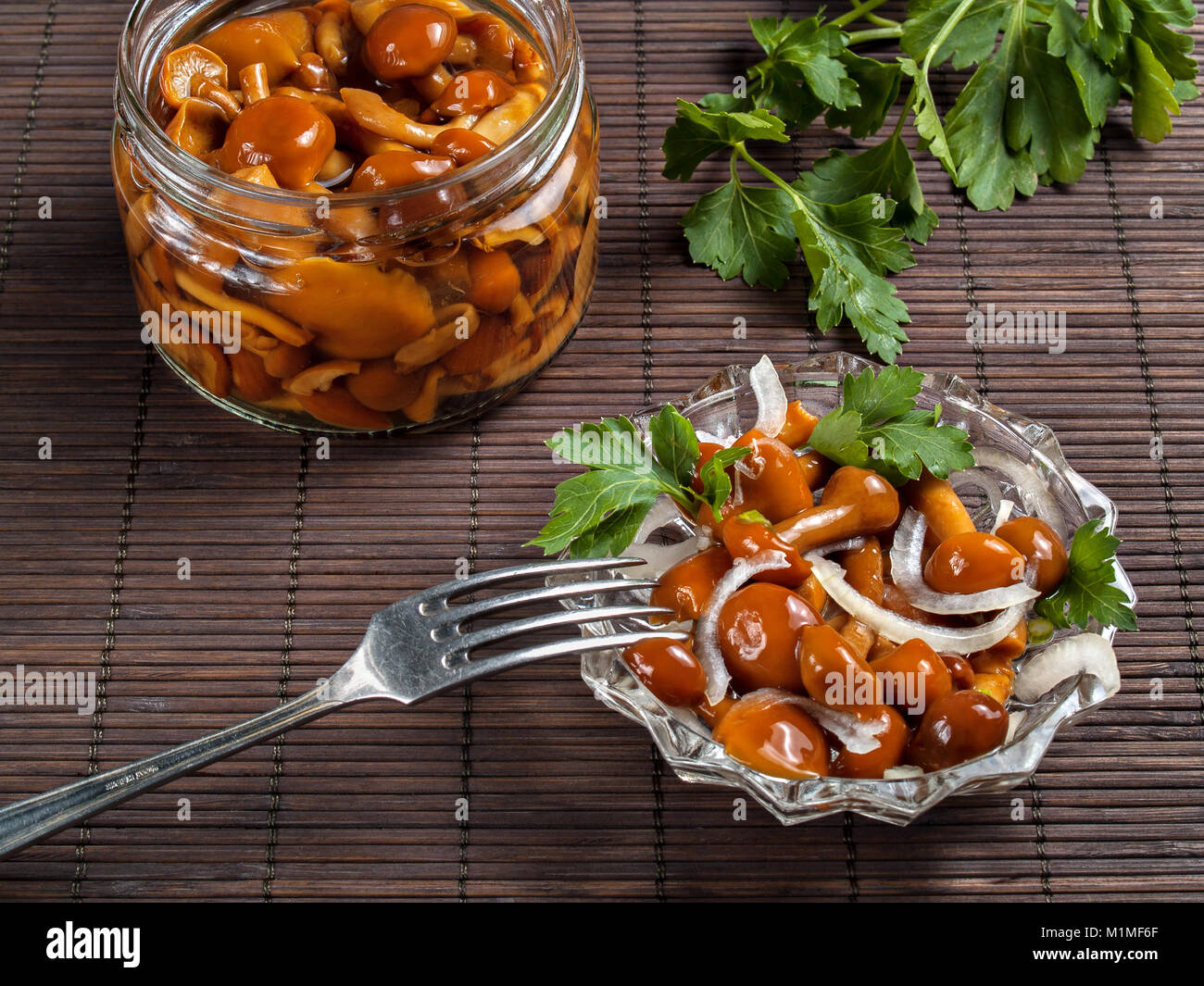 Decapare i funghi in un vaso e in un vaso di vetro condito con cipolla bianca e verde di stand sul tavolo pronti a mangiare Foto Stock