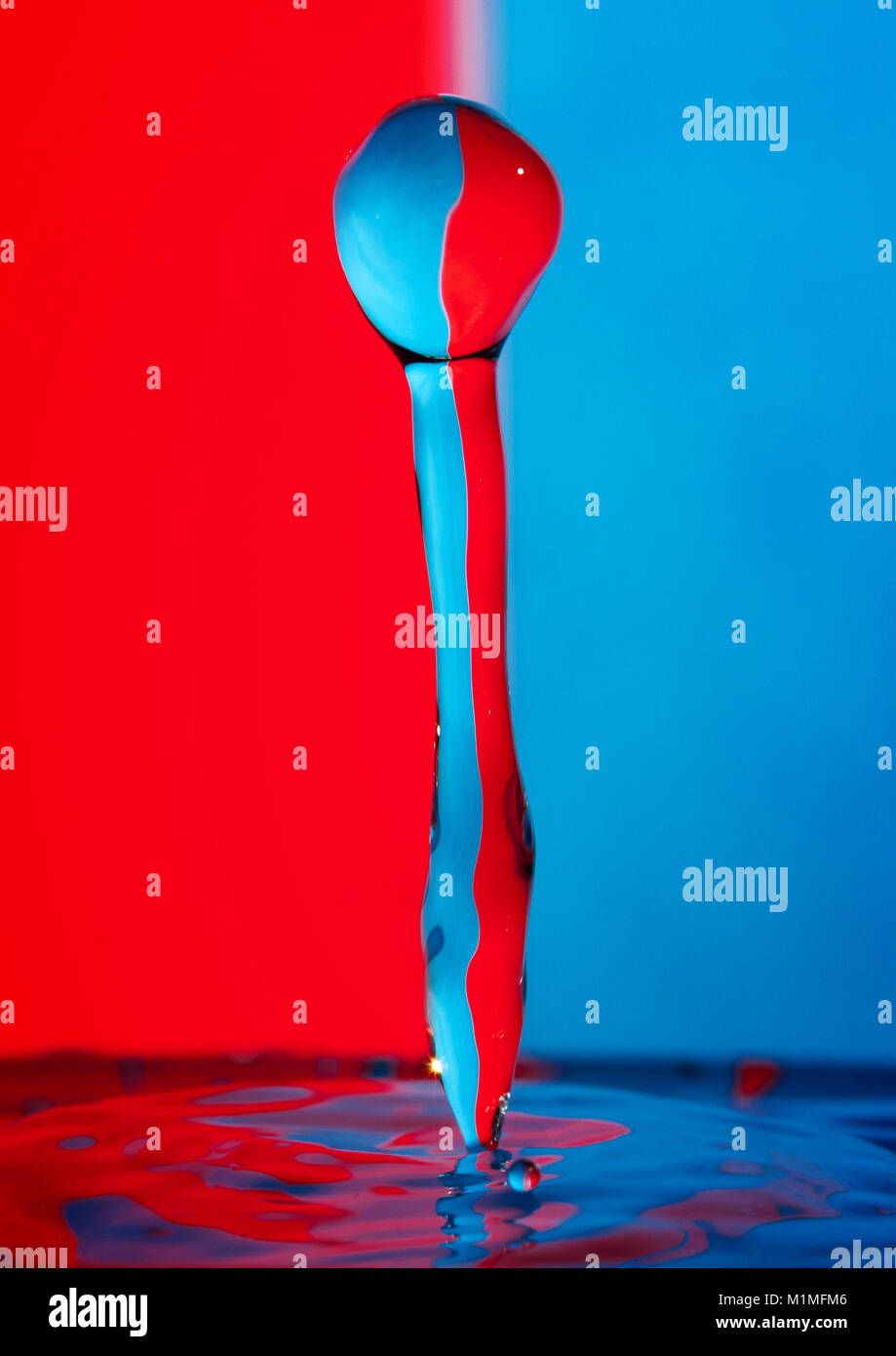 Goccia di acqua sulla colorata di rosso e sfondo blu Foto Stock