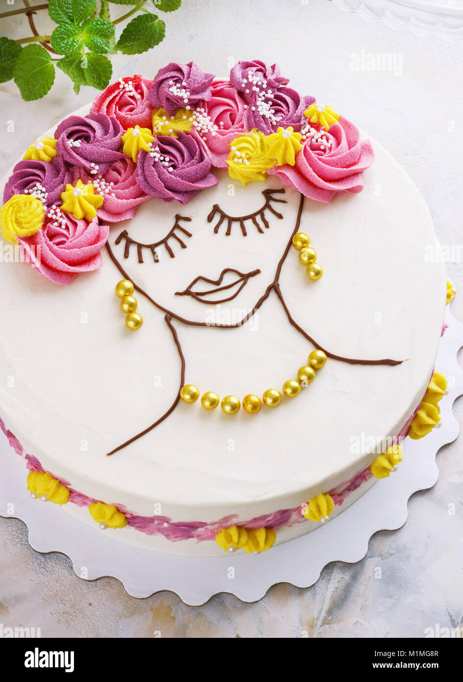 Festosa torta con crema di fiori e una ragazza faccia su uno sfondo luminoso Foto Stock