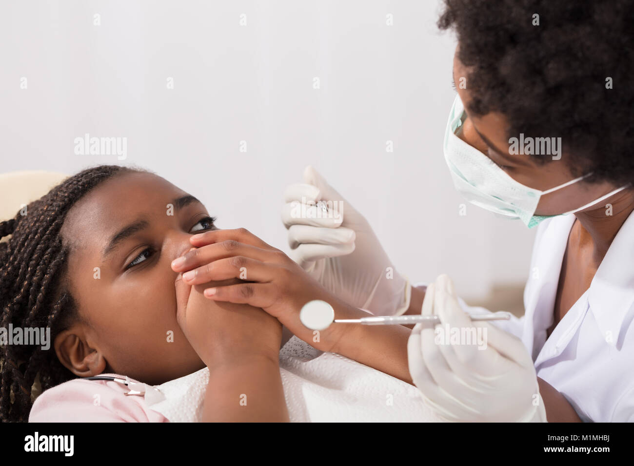 Spaventata ragazza che copre la bocca con le mani al dentista Foto Stock